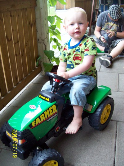 Ludwig sitter på sin nya traktor som han fått av mormor och Pajen.