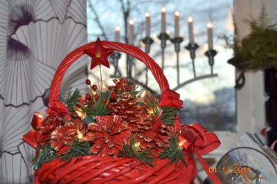 Julpynt på bordet i köket. En röd korg med pynt och lampor i.